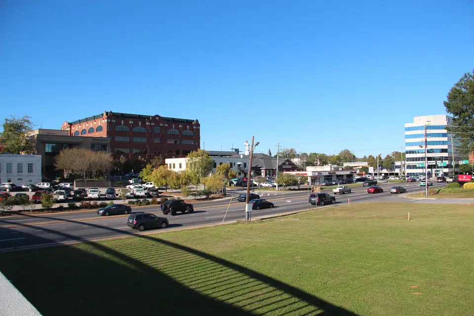 Downtown Gainesville parkway looking east past red-brick offices, a parking lot and a glass office tower