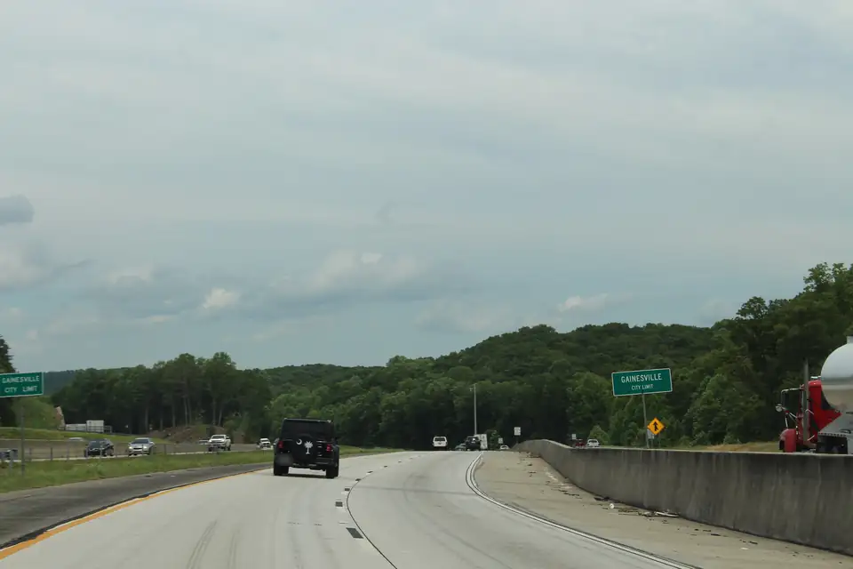 Interstate 985 northbound passing green Gainesville City Limit signs on both sides of the road